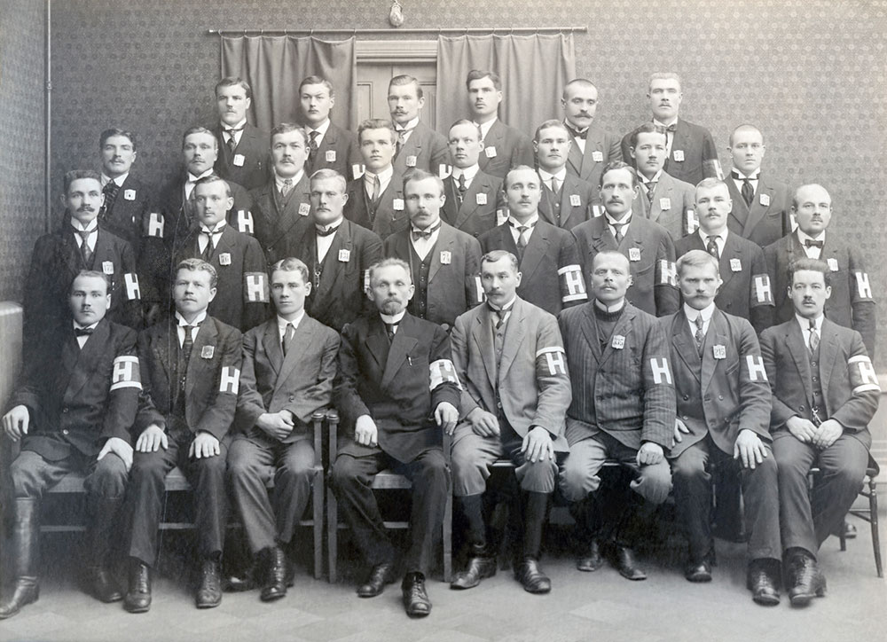 Maaliskuun vallankumouksen jälkeen vuonna 1917 järjestysvalta Suomessa ajautui paikallisille järjestyskaarteille ja –miehistöille, jotka käyttivät usein tunnuksenaan käsivarsinauhaa. Helsingissä perustettiin maaliskuussa kaupungin järjestystoimikunta, jonka alaisena toimivan miliisin nauhassa oli iso H-kirjain punaisella pohjalla. Kuva: Kansan arkisto.